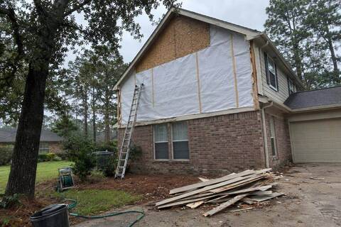 Gable end with the old siding removed and house wrap exposed, a ladder against the wall