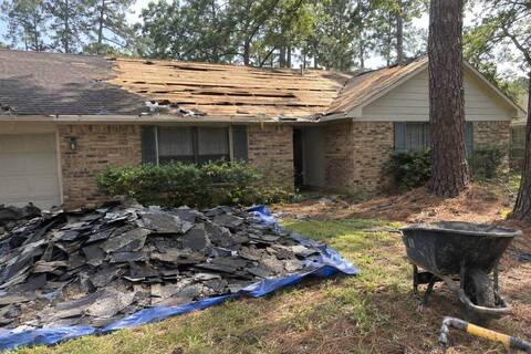 Tear-off in progress on a single-story brick house, old plank decking exposed