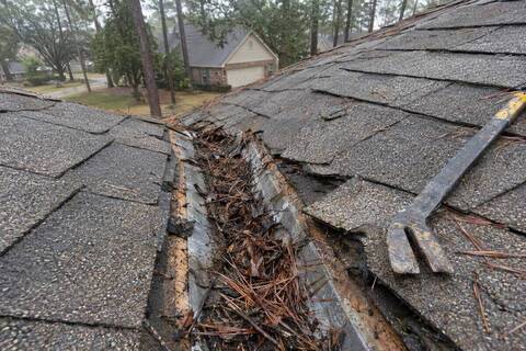 Roof valley with the shingles cut back to show the metal underneath, packed with pine needles